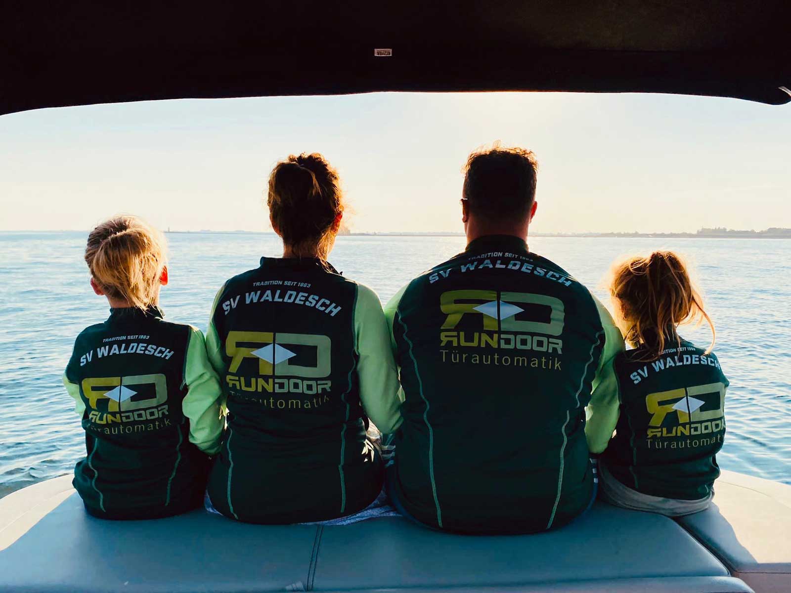 Trikot auf Tour - Familie sitz am Bug eines Bootes und schaut aufs offene Meer