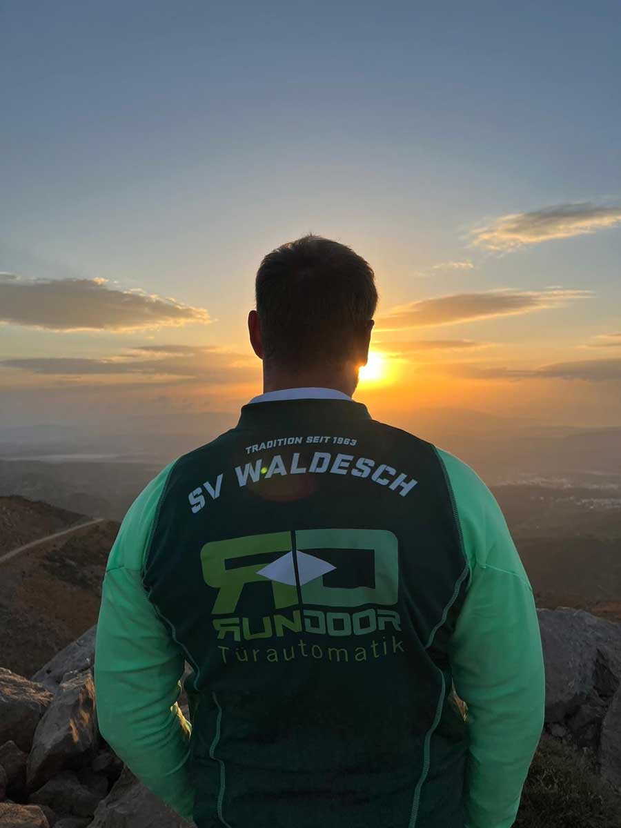 Trikot auf Tour - Junger Mann genießt den Sonnenuntergang ganz hoch in den Bergen 